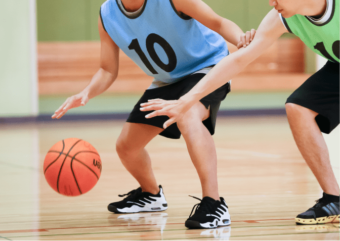 室内コートでバスケットを楽しむ二人の選手、試合の熱気が伝わる瞬間