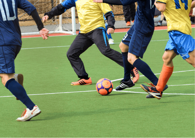 人工芝のフィールドでサッカーをする選手たち