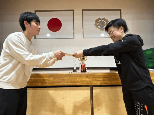 日本の旗の前で賞を授与する場面