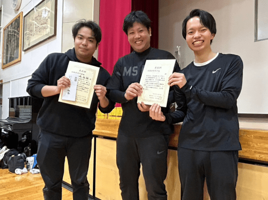 黒いスポーツウェア姿の3人が賞状を手に笑顔で並んでいる